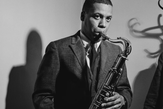 A black and white photo of Wayne Shorter playing a saxophone around 1960