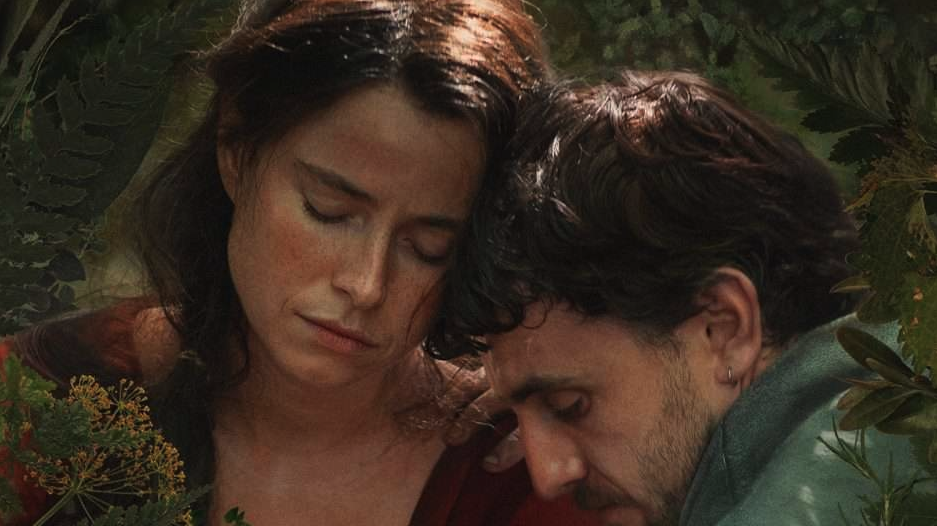 A close-up photo showing the faces of Jessie Buckley as Agnes and Paul Mescal as William Shakespeare in the movie Hamnet. Both actors are shown with their faces in closeup and their faces and eyes cast down.
