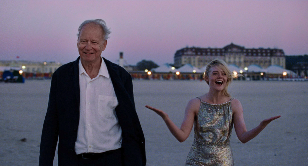 Stellan Skarsgård and Elle Fanning walk on a beach at dawn in the film Sentimental Value