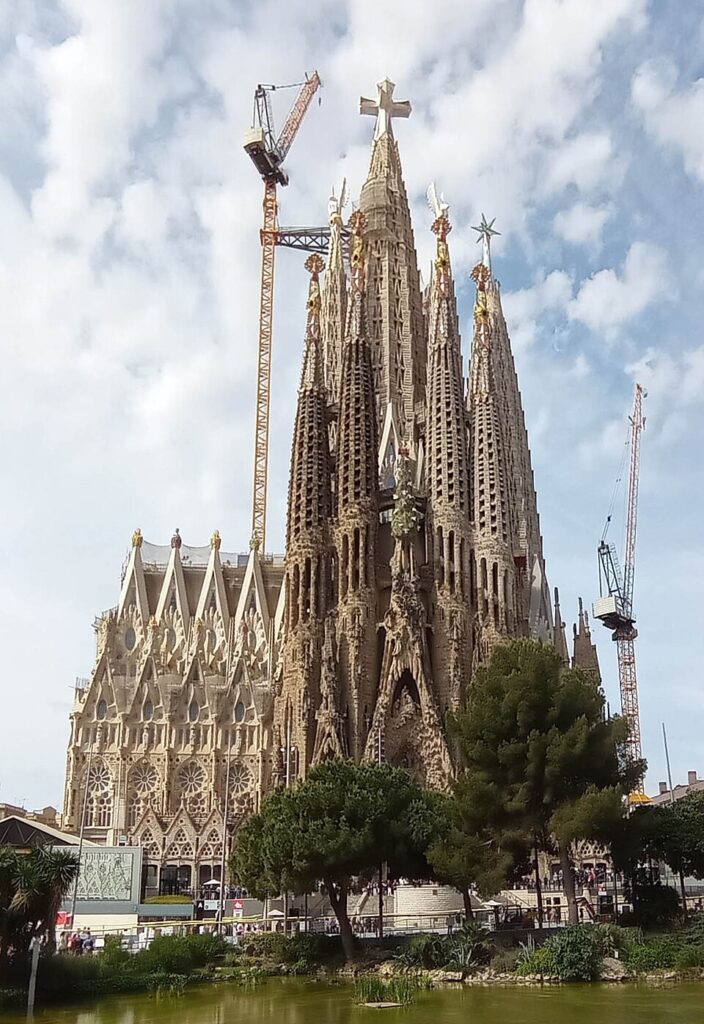 The full height of Sagrada Família is viewed in May 2026, just after its tower was erected. Construction cranes are still in place.